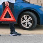 Uomo che prende il triangolo d'emergenza da posizionare davanti all'auto incidentata