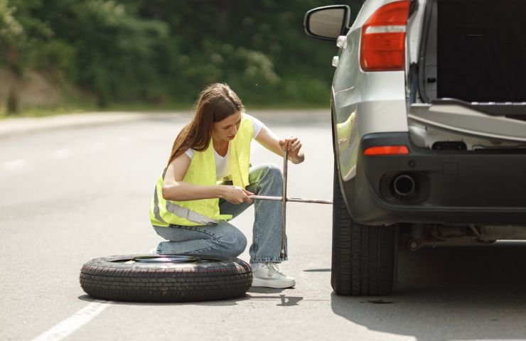 Automobilista sostituisce gomma forata