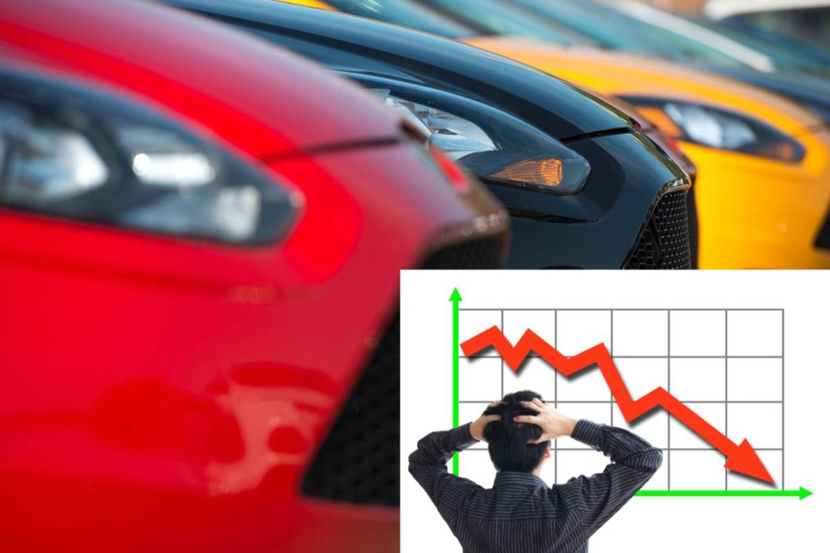 Alcune auto e in basso a destra un grafico in discesa a un uomo di spalle con le mani nei capelli