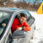 Un'automobilista su un fondo innevato. A destra il simbolo di richiamo all'attenzione