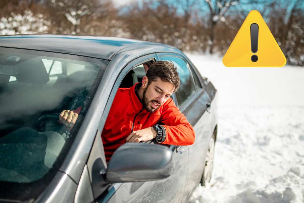 Un'automobilista su un fondo innevato. A destra il simbolo di richiamo all'attenzione