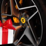 La ruota di una Ferrari con il logo e a sinistra il disegno di un pacco regalo