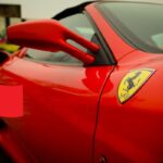 Una Ferrari e in basso a sinistra il disegno di una mano che sventola una bandierina cinese