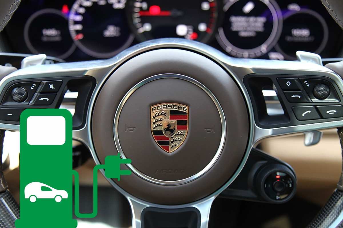 Il logo Porsche sul volante e in basso a sinistra il disegno di una colonnina per auto elettriche