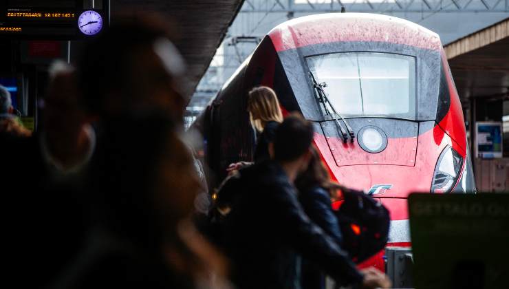 Un treno in stazione e delle persone sulla banchina in attesa