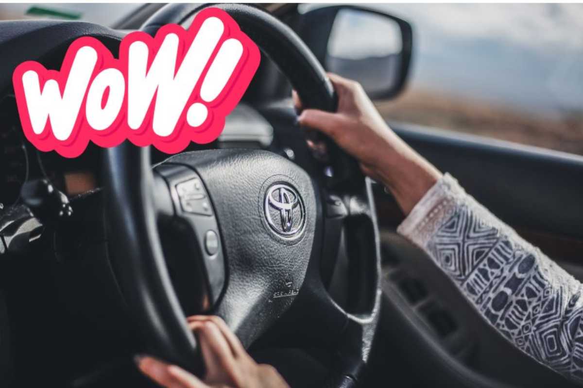 Una dona al volante di una Toyota e in alto  la scritta wow