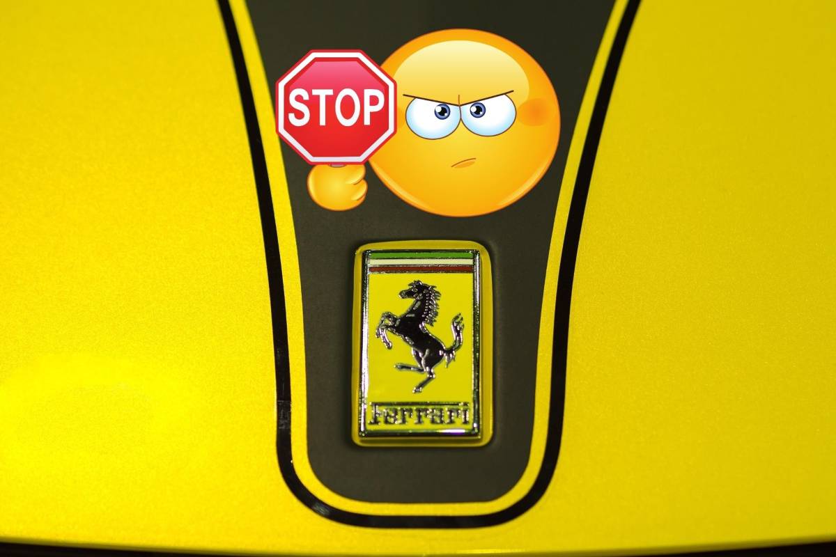 Il cofano di una Ferrari gialla con il logo e il nome e sopra un emoticon con il cartello Stop