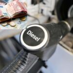 Una pompa di carburante diesel e un portafoglio con delle banconote e monete