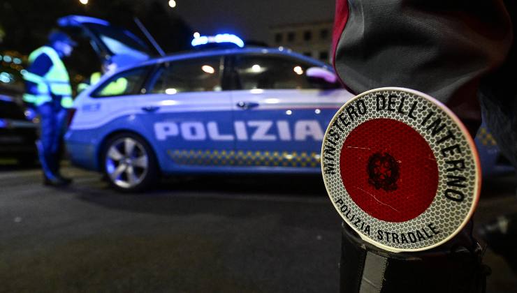 Un dettaglio della divisa della Polizia Stradale e in fondo l'auto di ordinanza